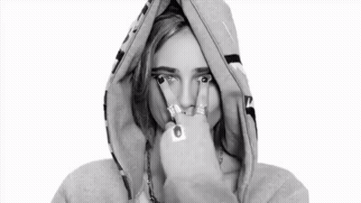 A Black And White Photo Of A Woman Wearing A Hoodie And Making A Peace Sign . GIF