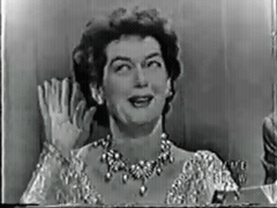 A Black And White Photo Of A Woman Wearing A Necklace Waving Her Hand . GIF
