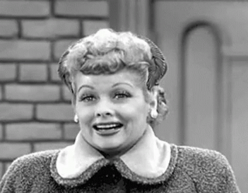 A Black And White Photo Of A Woman Wearing A Sweater And Smiling . GIF