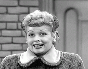 A Black And White Photo Of A Woman Wearing A Sweater And Smiling . GIF