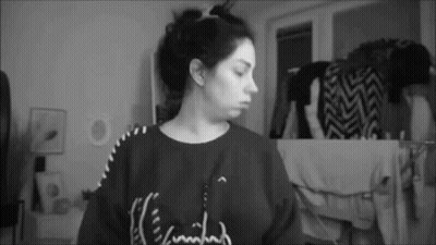 A Black And White Photo Of A Woman Wearing A Sweater That Says ' I 'M Tired ' On It . GIF