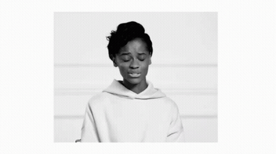 A Black And White Photo Of A Woman Wearing A White Hoodie And Looking At The Camera . GIF