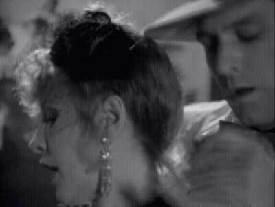 A Black And White Photo Of A Woman Wearing Earrings And A Man Wearing A Hat GIF