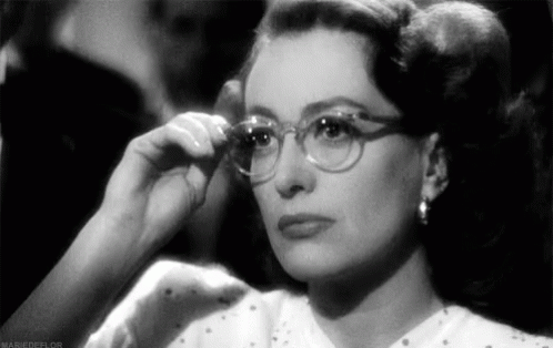 A Black And White Photo Of A Woman Wearing Glasses And Earrings . GIF