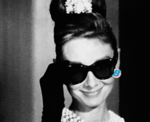 A Black And White Photo Of A Woman Wearing Sunglasses And A Tiara GIF