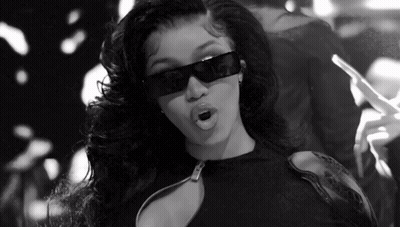 A Black And White Photo Of A Woman Wearing Sunglasses And Holding A Cigarette . GIF