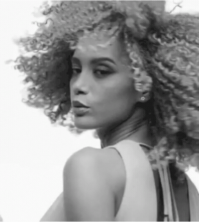 A Black And White Photo Of A Woman With Curly Hair And Earrings GIF