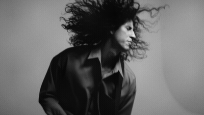 A Black And White Photo Of A Woman With Curly Hair GIF
