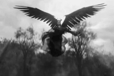 A Black And White Photo Of A Woman With Large Wings Flying In The Air . GIF