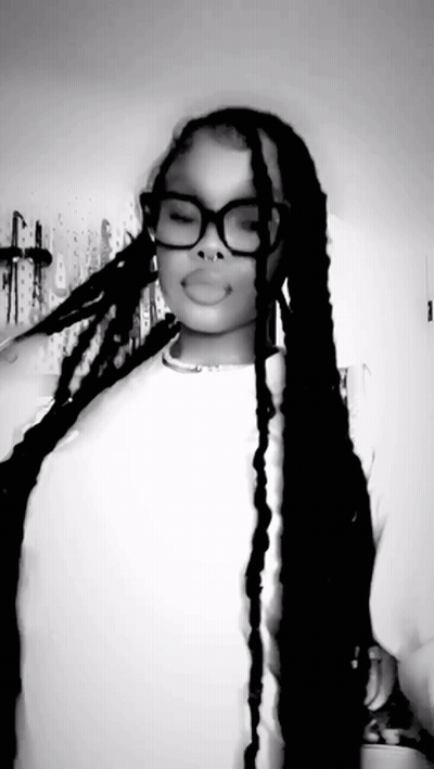 A Black And White Photo Of A Woman With Long Braids Wearing Glasses And A Nose Ring . GIF