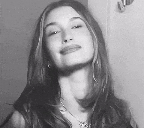 A Black And White Photo Of A Woman With Long Hair And A Necklace . GIF