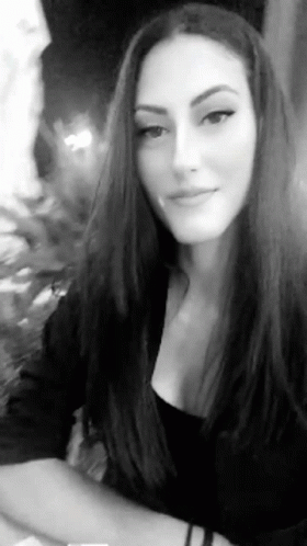 A Black And White Photo Of A Woman With Long Hair In A Black Top . GIF