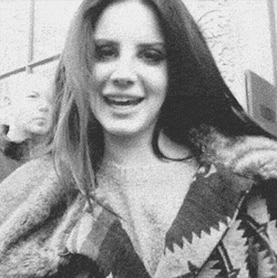 A Black And White Photo Of A Woman With Long Hair Wearing A Fur Coat And Smiling . GIF
