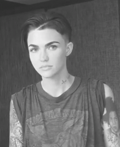 A Black And White Photo Of A Woman With Short Hair And A Tattoo On Her Neck GIF