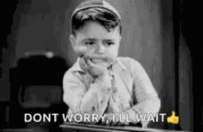 A Black And White Photo Of A Young Boy Sitting At A Desk With His Hand On His Chin And A Thumbs Up . GIF