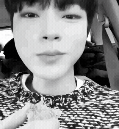 A Black And White Photo Of A Young Boy Sitting In A Car Eating A Sandwich . GIF