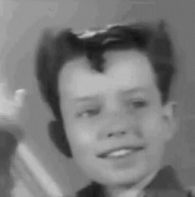 A Black And White Photo Of A Young Boy With A Mohawk Smiling . GIF