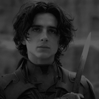 A Black And White Photo Of A Young Man Holding A Knife GIF