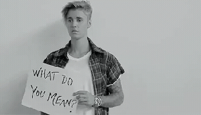A Black And White Photo Of A Young Man Holding A Sign That Says `` What Do You Mean '' . GIF