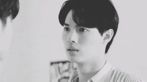 A Black And White Photo Of A Young Man In A Plaid Shirt Looking Over His Shoulder . GIF