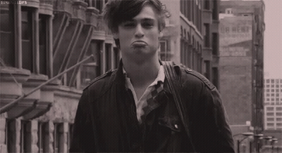 A Black And White Photo Of A Young Man Making A Funny Face While Walking Down A City Street . GIF