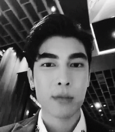 A Black And White Photo Of A Young Man 'S Face In A Suit And White Shirt . GIF