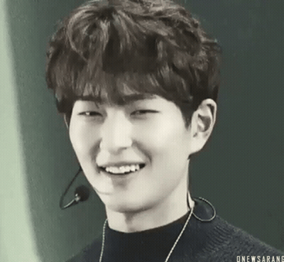 A Black And White Photo Of A Young Man Smiling With A Microphone Around His Neck . GIF
