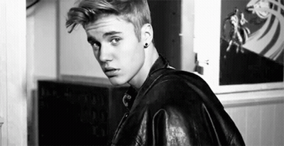 A Black And White Photo Of A Young Man Wearing A Leather Jacket And Earrings . GIF
