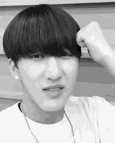 A Black And White Photo Of A Young Man With A Bangs Holding His Hair . GIF