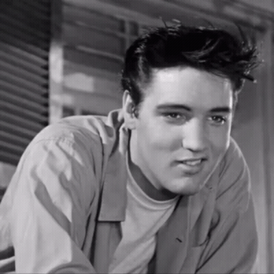 A Black And White Photo Of A Young Man With A Slight Smile On His Face GIF