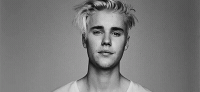 A Black And White Photo Of A Young Man With Blonde Hair And A White Shirt . GIF