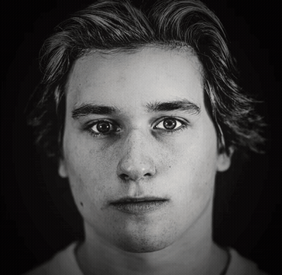 A Black And White Photo Of A Young Man With Freckles GIF