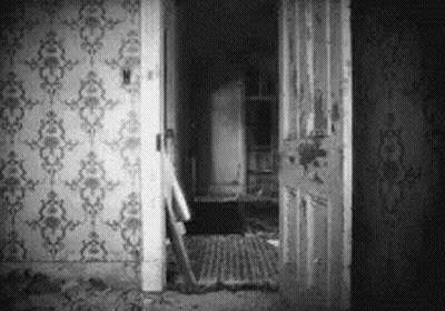 A Black And White Photo Of An Old House With A Door Open And A Staircase . GIF