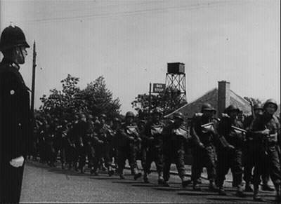 A Black And White Photo Of Soldiers Marching In Front Of A Sign That Says End Stop GIF