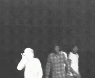 A Black And White Photo Of Three People Standing Next To Each Other In A Dark Room . GIF