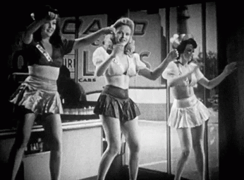 A Black And White Photo Of Three Women Dancing In Front Of A Store . GIF