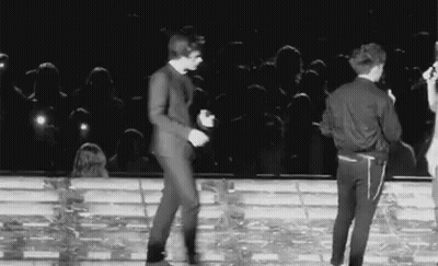 A Black And White Photo Of Two Men Dancing On A Stage . GIF
