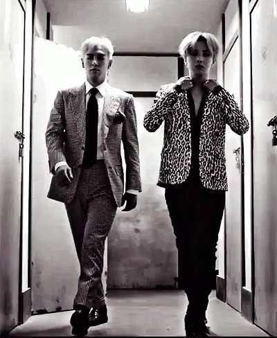A Black And White Photo Of Two Men In Suits And Ties Walking Down A Hallway . GIF