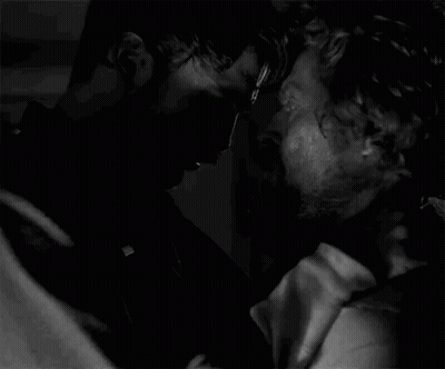 A Black And White Photo Of Two Men Kissing Each Other In A Dark Room . GIF