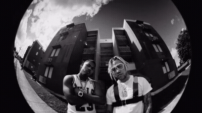 A Black And White Photo Of Two Men Standing In Front Of A Building With One Wearing A Number 9 Jersey GIF