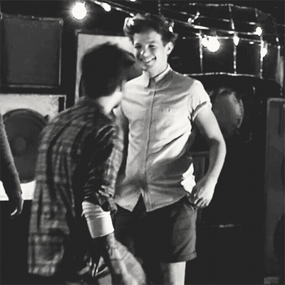 A Black And White Photo Of Two Men Standing Next To Each Other And Smiling . GIF