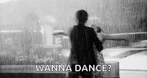 A Black And White Photo Of Two People Dancing In The Rain . GIF
