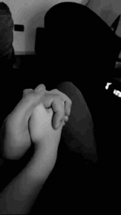 A Black And White Photo Of Two People Holding Hands . GIF