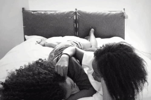 A Black And White Photo Of Two Women Laying On A Bed With Their Heads On Each Other GIF