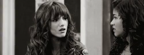 A Black And White Photo Of Two Women Standing Next To Each Other And Talking . GIF