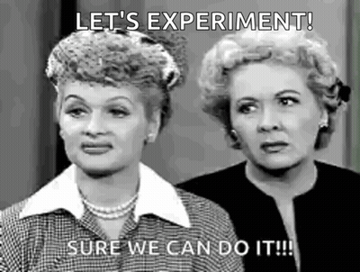A Black And White Photo Of Two Women Standing Next To Each Other . One Of The Women Is Saying `` Let 'S Experiment ! '' GIF