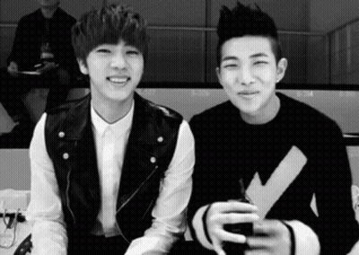 A Black And White Photo Of Two Young Men Sitting Next To Each Other And Smiling . GIF