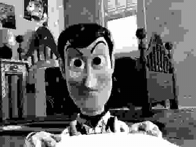 A Black And White Photo Of Woody From Toy Story Holding A Piece Of Paper In A Room . GIF