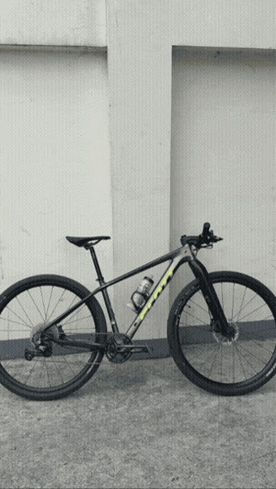 A Black And Yellow Bicycle Is Parked In Front Of A Wall GIF