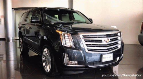 A Black Cadillac Escalade Is In A Showroom GIF
